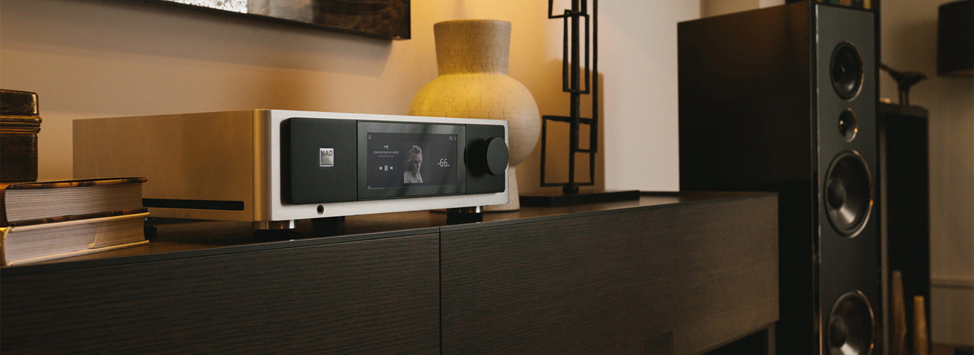 Audio equipment on a wooden surface with books and a lamp in a room setting